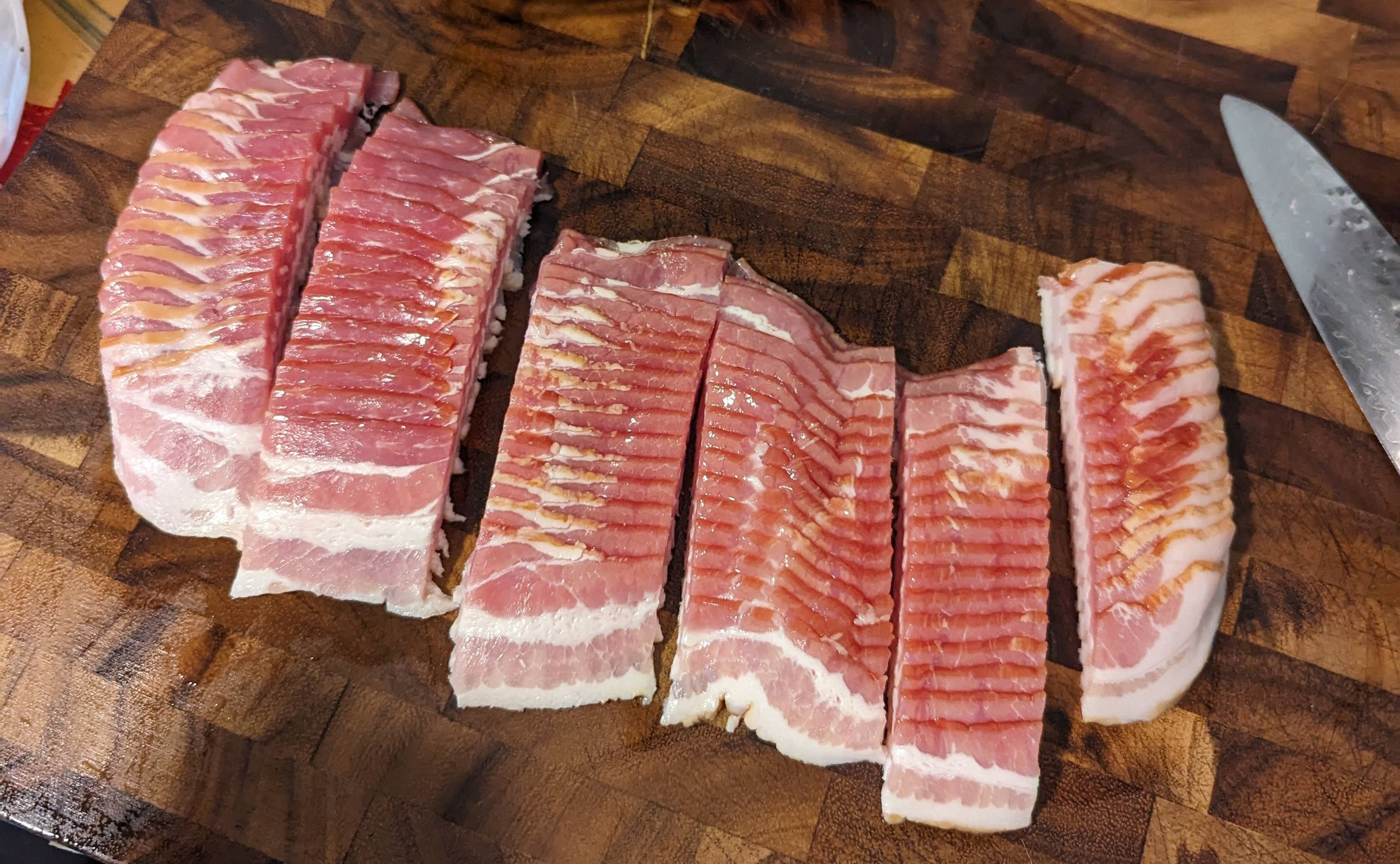 Cutting board with a one pound packet of bacon sliced into pieces.