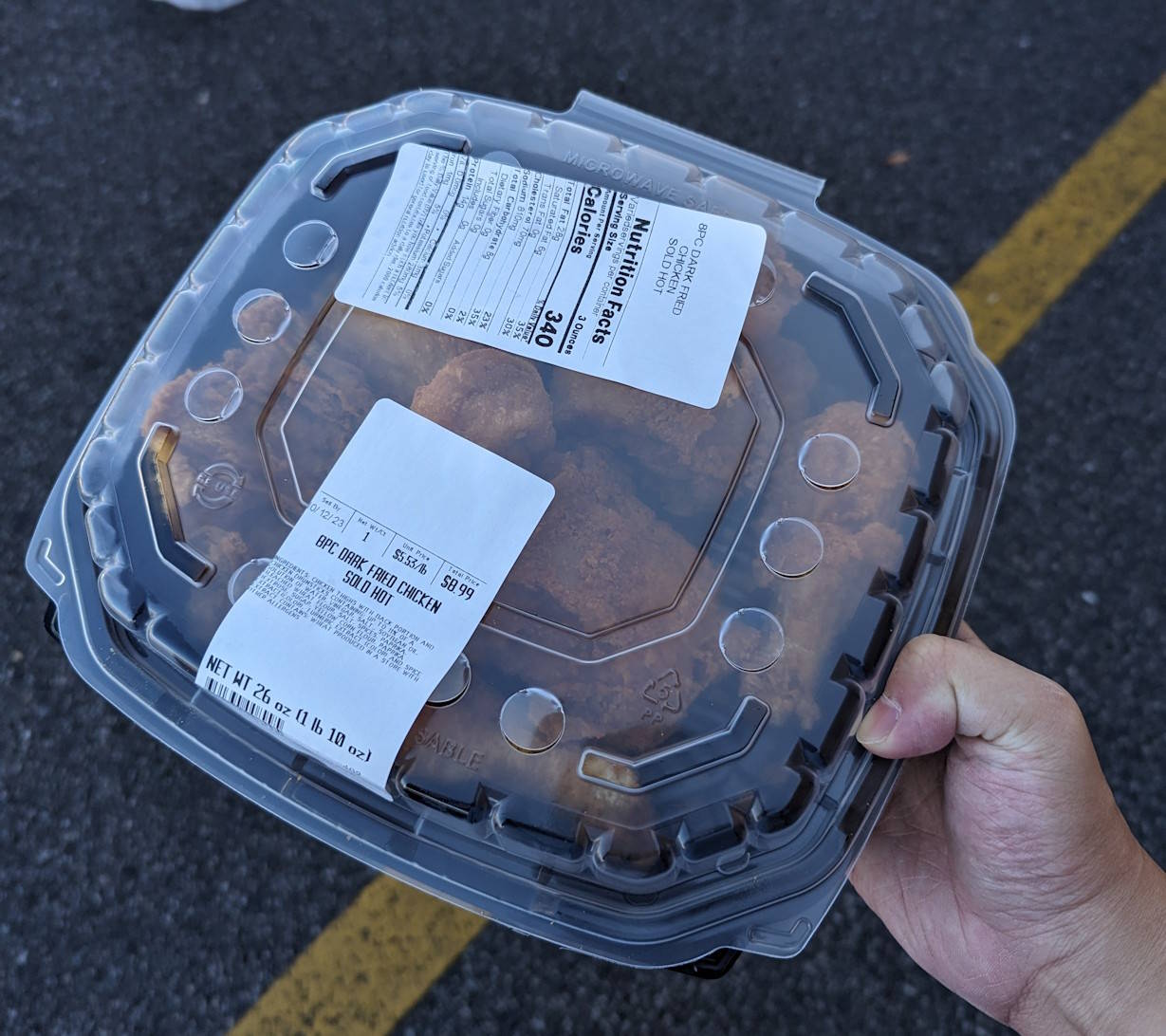 I'm holding an 8-piece box of dark fried chicken from ShopRite while walking in a parking lot. It's $9 for 8 pieces.
