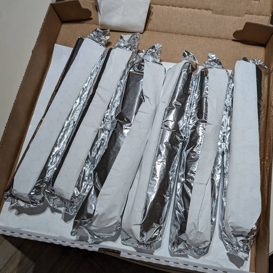 Six cheesesteaks wrapped in foil paper.